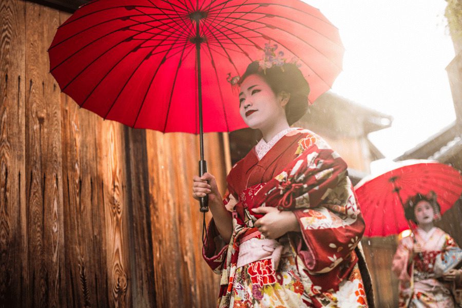 geishas au japon habillées en kimono rouge sous une ombrelle rouge à Kyoto