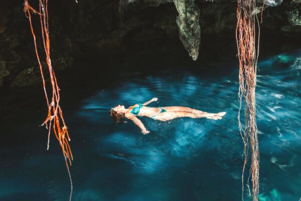 cenote Akumal au Mexique femme qui flotte sur le dos dans l'eau bleue dans une grotte